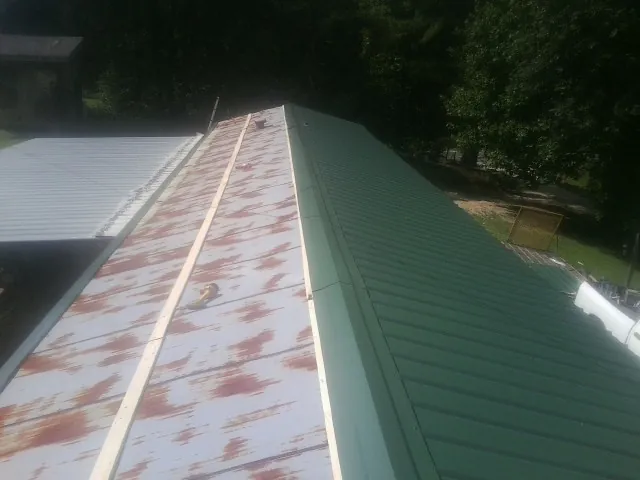 Old rusted panels beside newly installed green metal roofing — Wind Damage Roof Repair by Roofing Brothers in Schwenksville