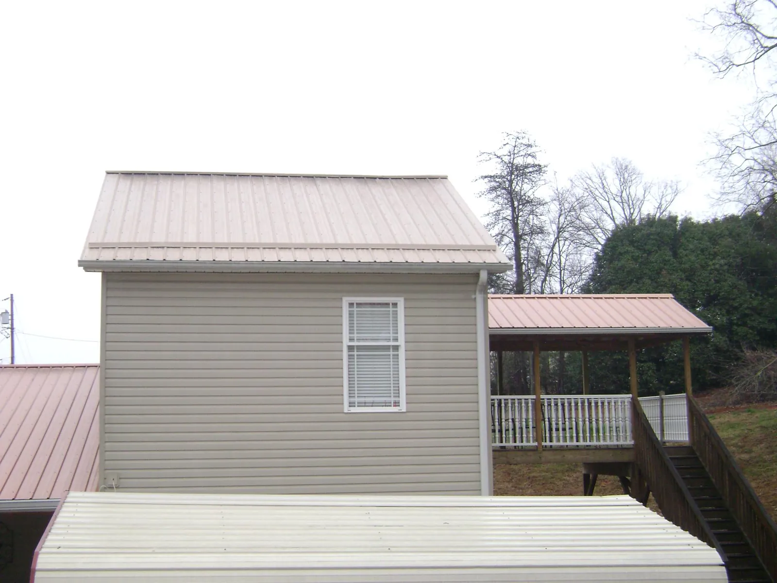 Tan metal roofs on a two story addition and attached porch, from a Roof Replacement job in Schwenksville