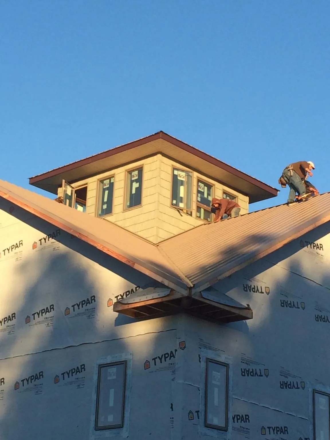 Roofers working around a rooftop cupola on a new metal roof at sunset — Roof Waterproofing in Schwenksville by Roofing Brothers